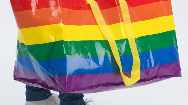 Unha persoa leva unha bolsa da compra STORSTOMMA coas cores do arco da vella. 