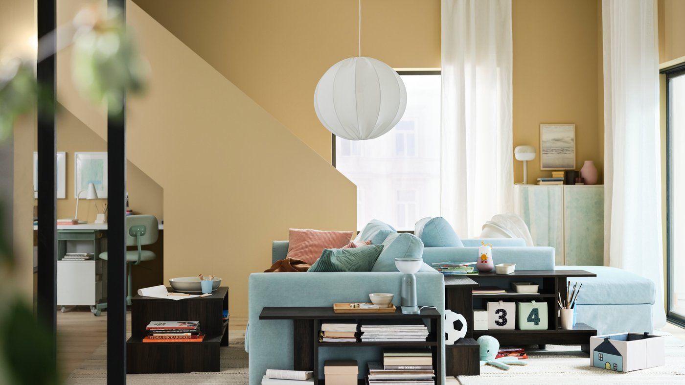 Unha sala de estar elegante con paredes amarelas e un sofá cama de tres prazas VIMLE en azul claro de costas a un chaiselongue VIMLE.