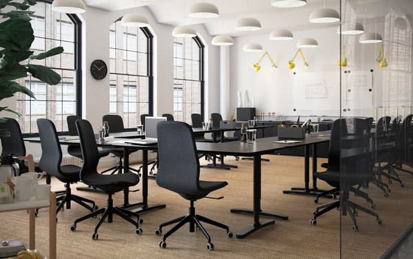 Unha sala de xuntas de planta aberta con escritorios en marrón-negro IKEA BEKANT e cadeiras xiratorias ergonómicas LÅNGFJÄLL en negro.
