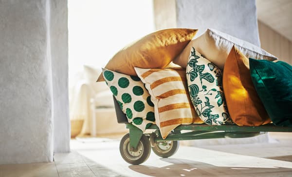 Unha variedade de coxíns con cores primaverais sobre un carriño con rodas.