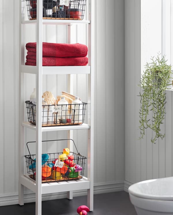Unit rak HEMNES berwarna putih dengan bakul dawai PLEJA berwarna hitam mempunyai tuala, mainan mandi, produk spa dan banyak lagi di atas empat para.