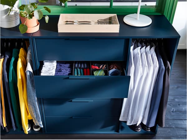 Unité de rangement IKEA NORDMELA bleu foncé avec un tiroir ouvert contenant des vêtements.