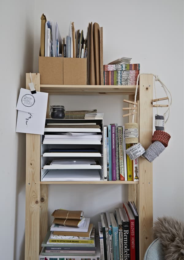 Uno scaffale carico di libri, foglietti e cartoncini.