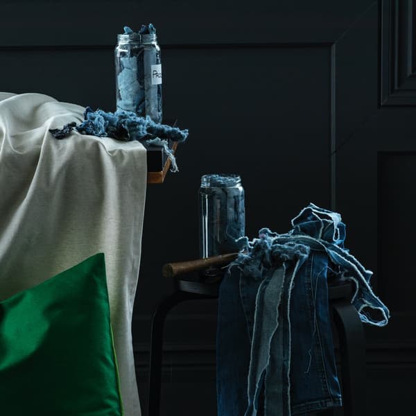 Uno sgabello nero con sopra scampoli di tessuto in jeans da riciclare.