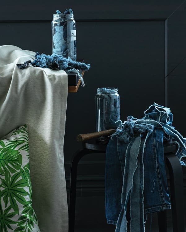 Uno sgabello nero con sopra scampoli di tessuto in jeans da riciclare.