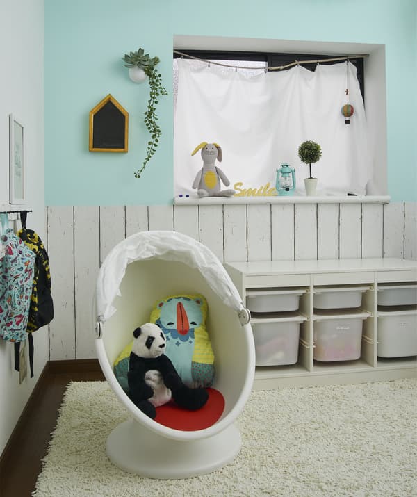 Uno spazio di gioco con contenitori per giocattoli e dei peluche in una poltrona girevole IKEA PS LÖMSK su un tappeto. Sotto la finestra, uno scaffale con contenitori TROFAST.