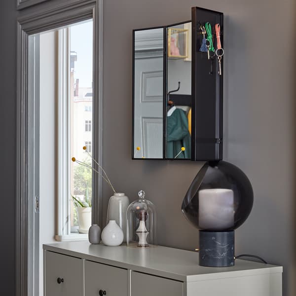 Uno specchio KARMSUND montato a parete e delle chiavi appese ai ganci sul retro degli specchi laterali regolabili - IKEA