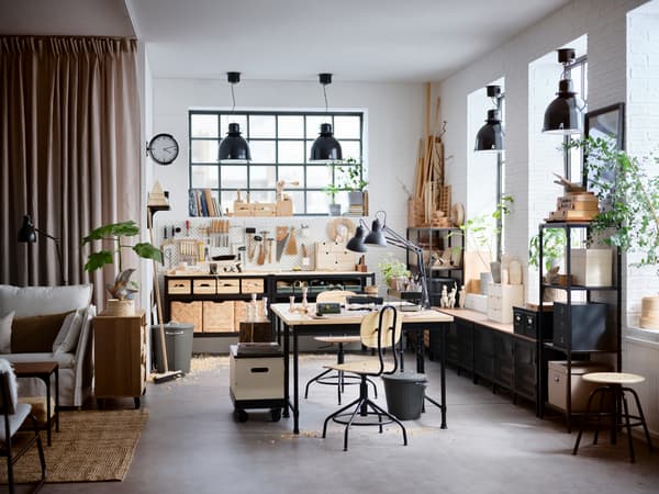 Uno studio in stile industriale con un banco da lavoro BROR al centro e scaffali FJÄLLBO contro le pareti - IKEA.