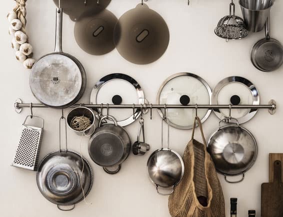Unterschiedlichstes universelles Kochzubehör der KLOCKREN Serie von Kochtopfdeckeln, über Durchschlag und Dampfgareinsatz zu Silikondeckeln, hängt an einer hellen Wand.