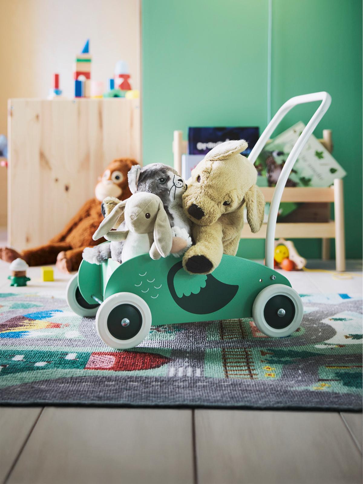UPPSTÅ toddler walker completely full of IIKEA soft toys, with a green wall behind it and the VALLABY rug underneath, as Christmas gifts