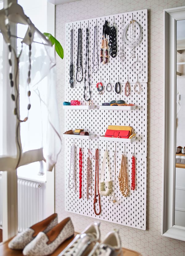 Use multiple IKEA SKÅDIS white pegboards to hang your jewelry and accessories, using add-on white shelves, hooks, pegs and elastic coords.