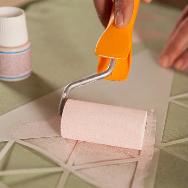 Using a stencil and a paint roller, stencil a pink triangle onto the fabric.