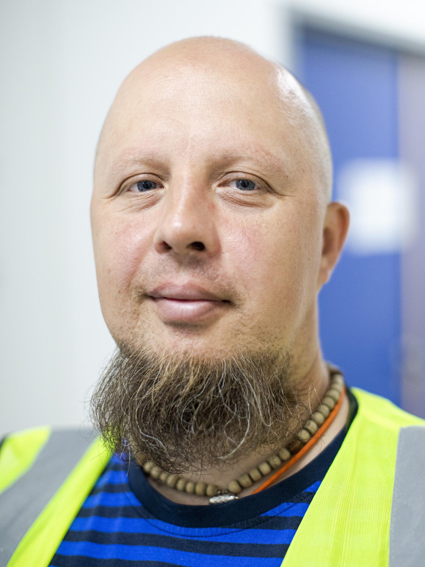 Uśmiechnięty Andrei z Białorusi w bluzce w niebieskie paski i odblaskowej kamizelce.