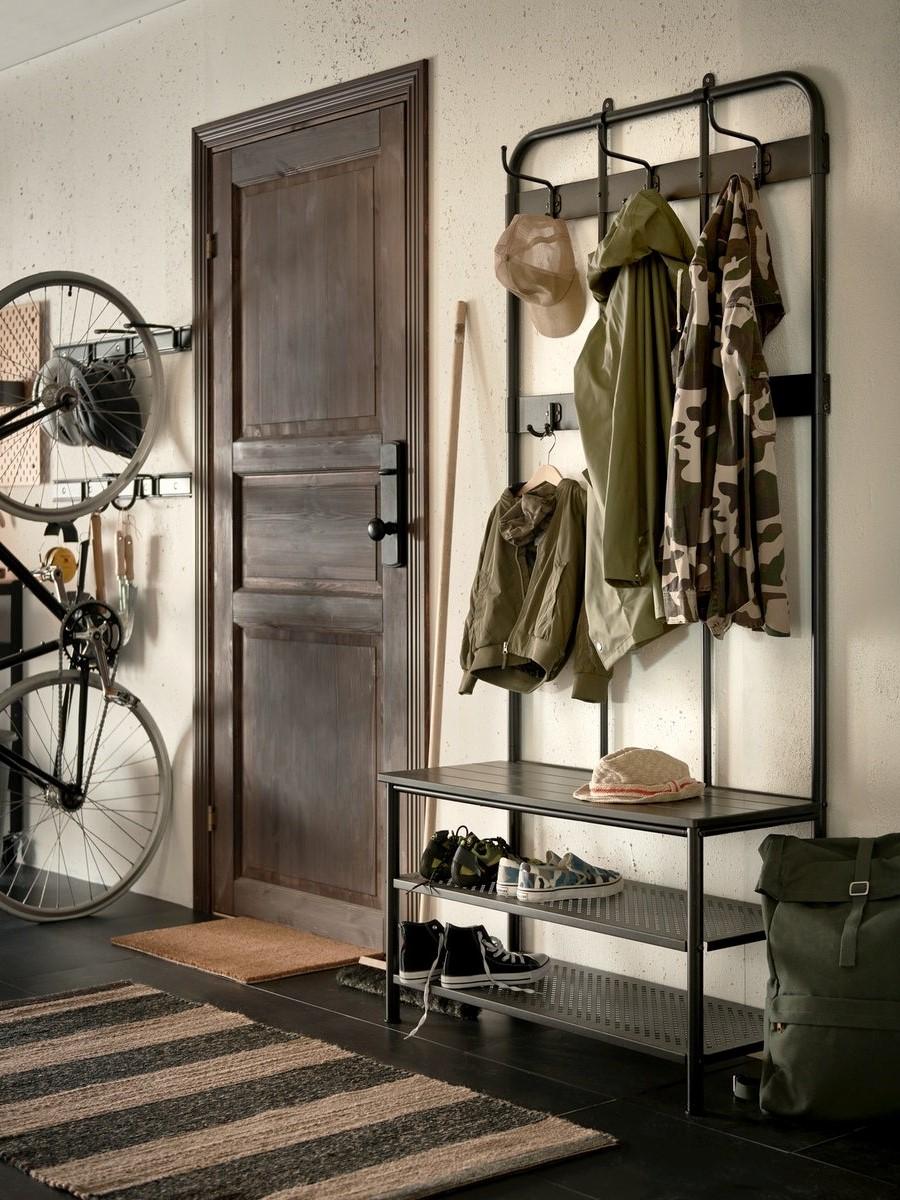 Ustawiony w korytarzu czarny metalowy wieszak PINNIG z półkami na buty i haczykami na kurtki.