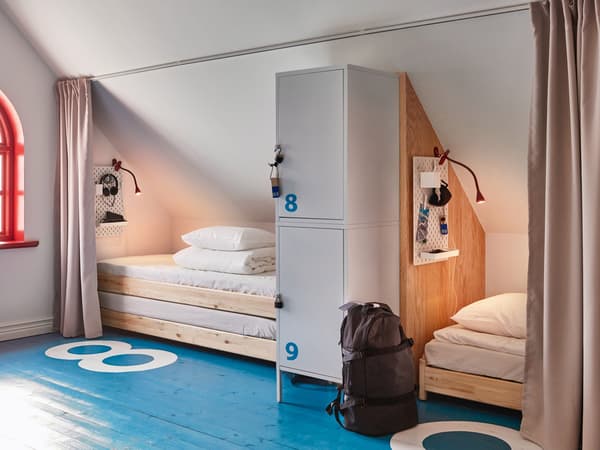 UTÅKER stackable beds behind privacy curtains, separated by a locker cabinet in an attic bedroom.