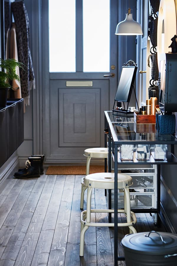 Utilise une table étroite, deux tabourets, quelques organiseurs, des dessertes et un miroir éclairé pour créer un petit coin coiffeuse.