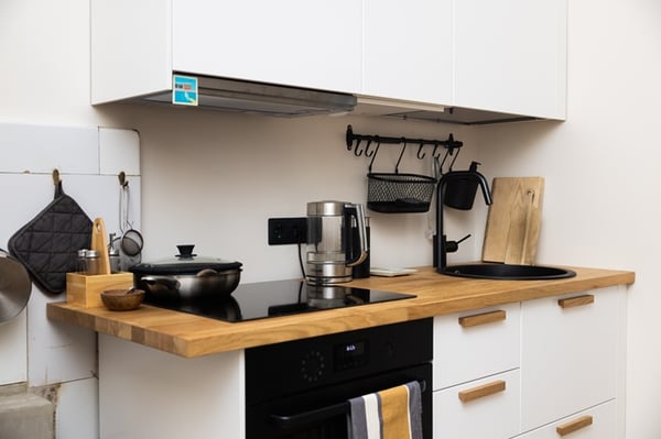 Узкая кухня с мойкой у окна, растениями на подоконнике и функциональной рабочей зоной.