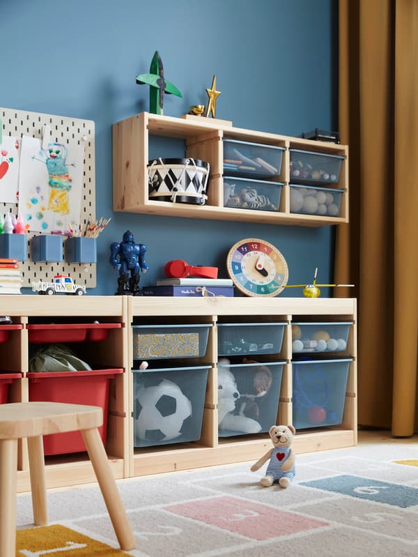 V detskej izbe s úložnými dielmi TROFAST sedí plyšový medvedík FABLER BJÖRN na koberci STÄPPSPARV.