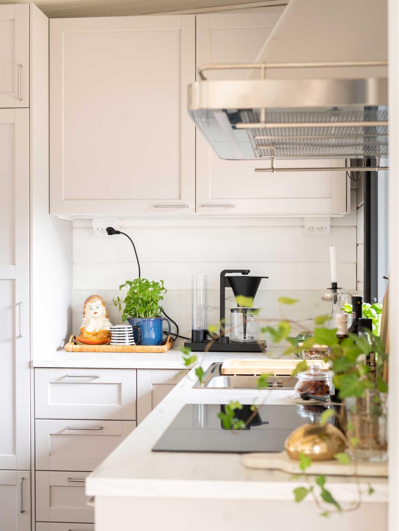 Vaaleanharmaa METOD LERHYTTAN-keittiö ja hopeinen liesituuletin.