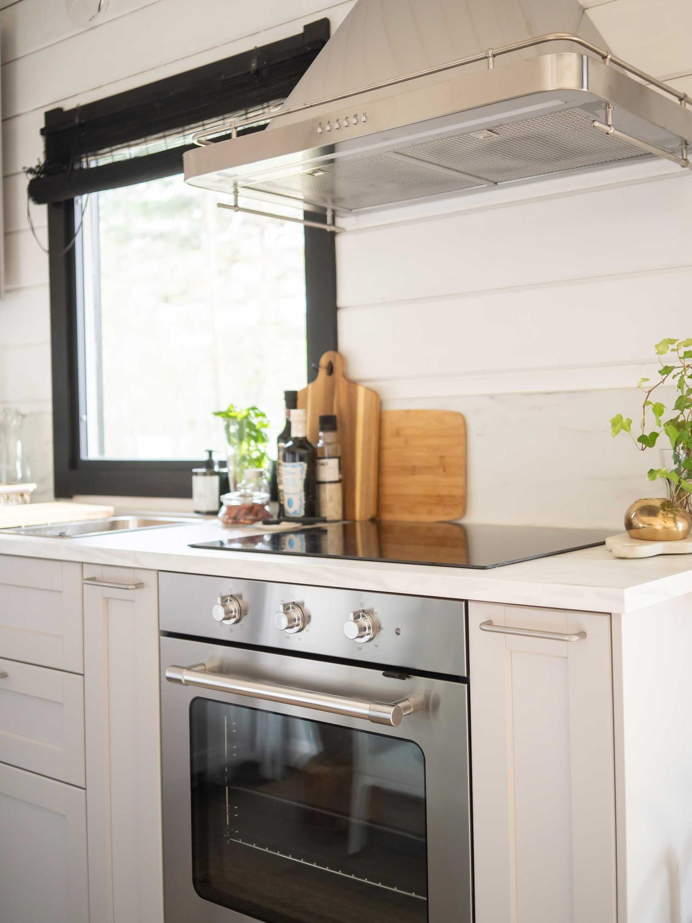 Vaaleassa keittiössä on hopeinen liesituuletin ja samanvärinen uuni.