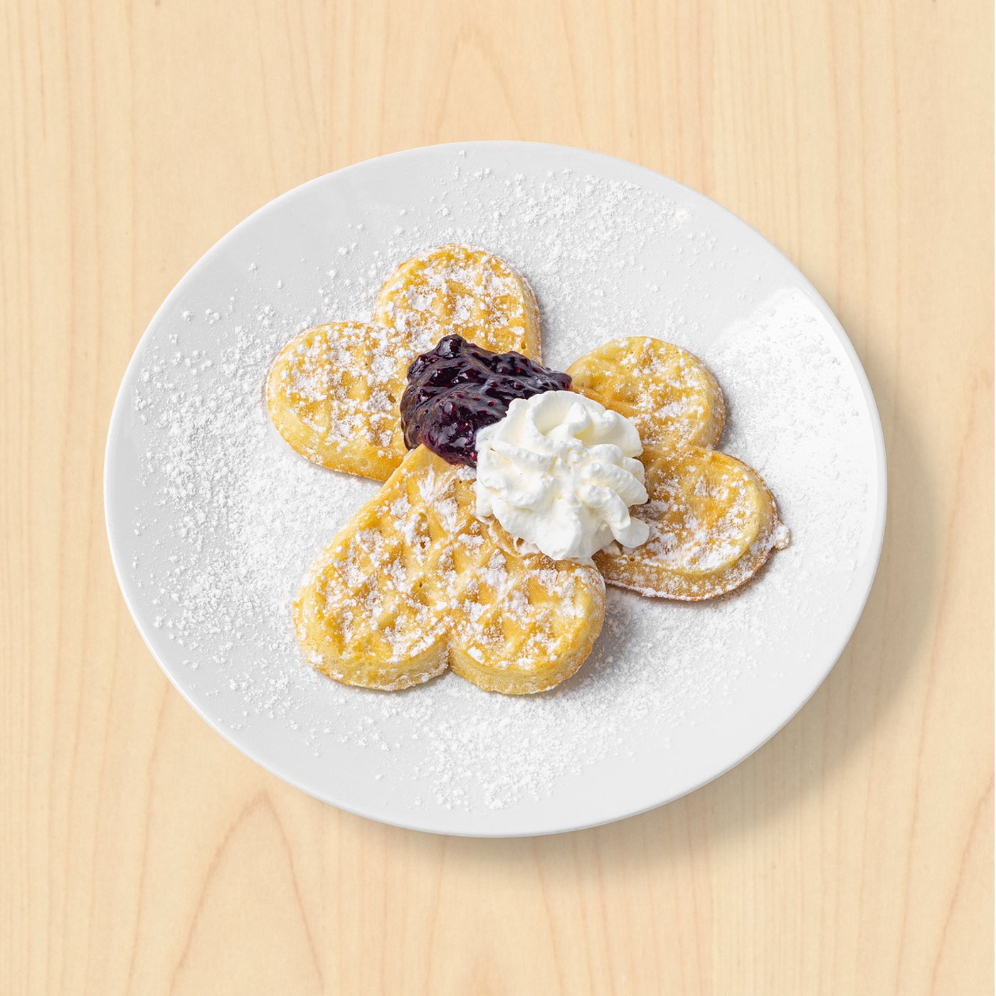 Vafle se šlehačkou a džemem na talíři. 