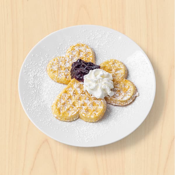 Vafle se šlehačkou a džemem na talíři. 