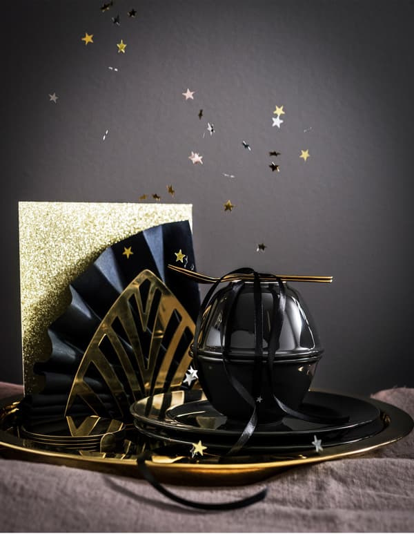 Vaixela dourada GLATTIS de IKEA e artigos de mesa VARDAGEN negros ordenados con papel brillante e ventiladores de panos de mesa de papel.