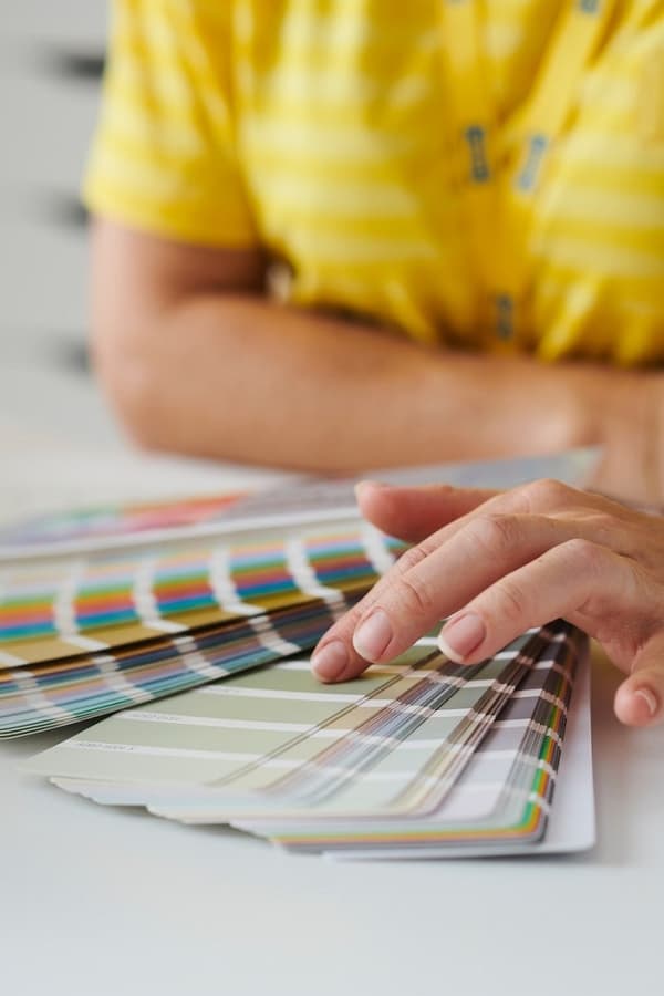 Vaizdas iš arti: IKEA interjero dizainerė ranka sklaido spalvų paletę ir renkasi dažų pavyzdžius.