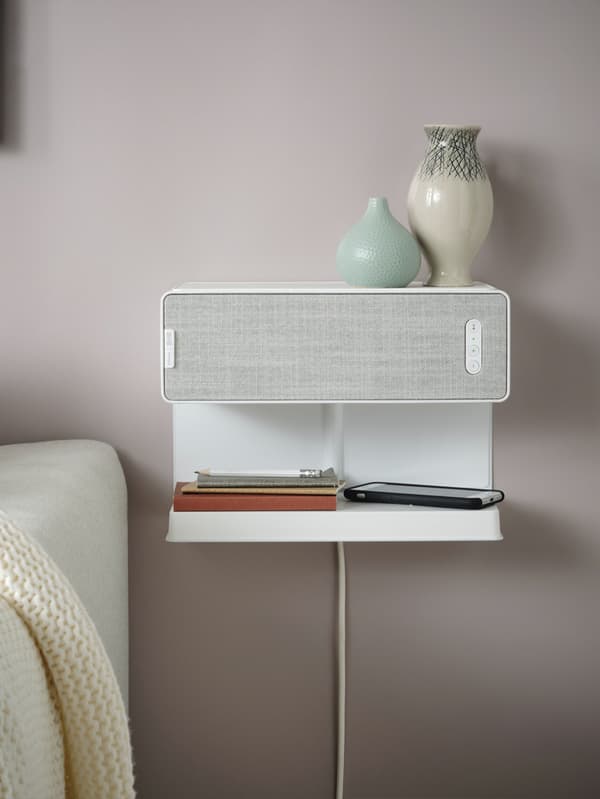 Van egy hangszóró a falra szerelve, rajta egy polc és vázák.