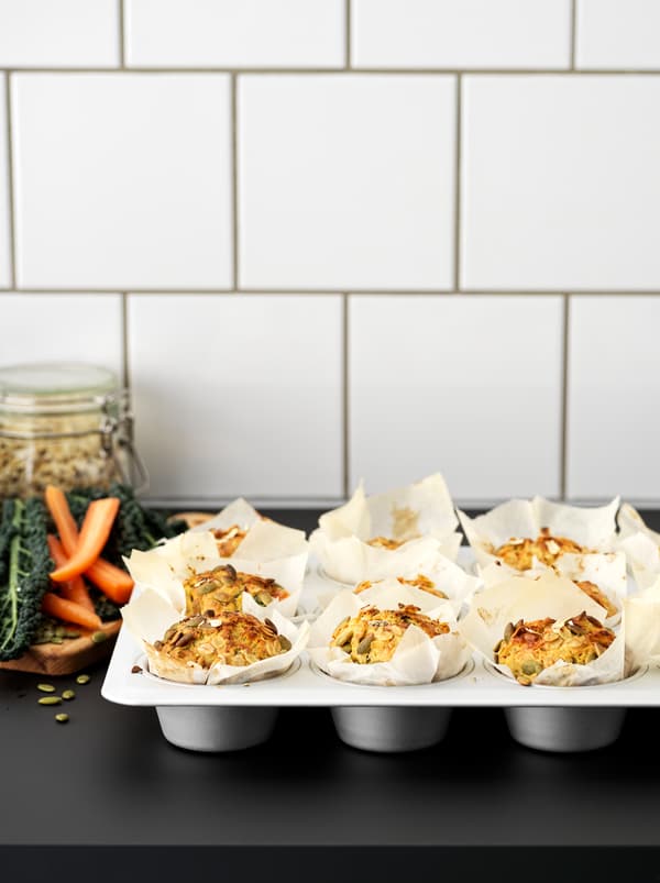 มัฟฟินสิบสองชิ้นทำจากเมล็ดฟักทองและแครอทในถาดอบทำจากเหล็ก VARDAGEN/วาร์ดาเกน บนท็อปครัวสีดำ