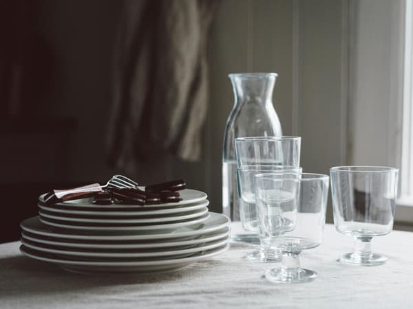 VARDAGEN tallerkener og IKEA 365+ glas står stablet på et bord med en dug.