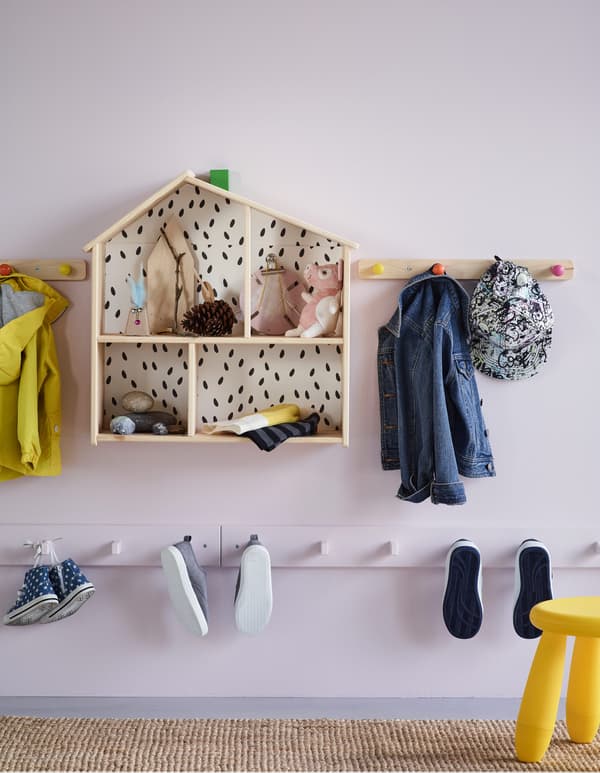 Varias guías con ganchos nun corredor colocados a unha altura adaptada aos nenos para colgar abrigos e zapatos.