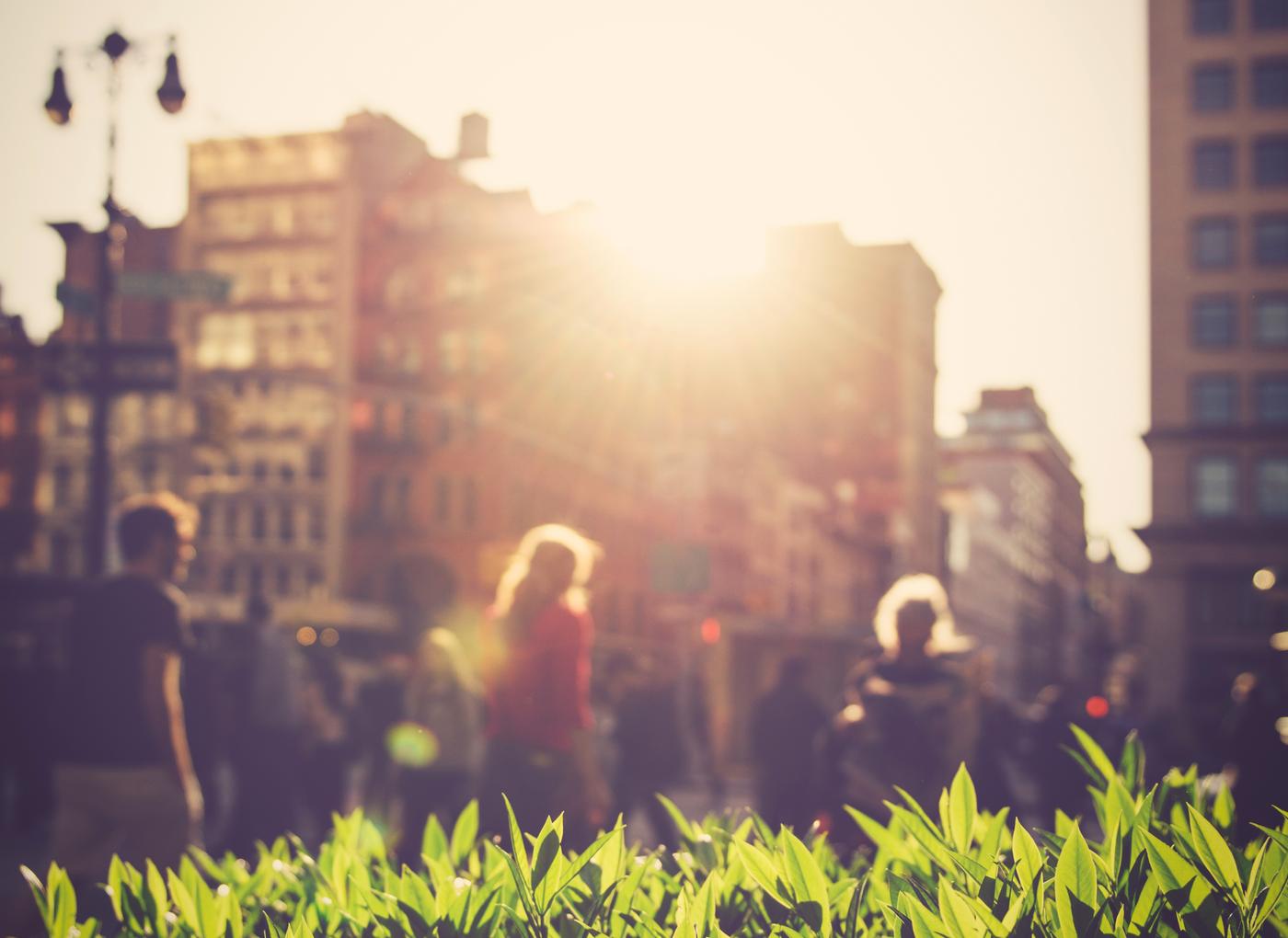 Varias personas paseando en una ciudad al atardecer.