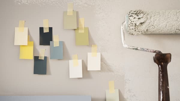 Various colour suggestions hanging on a wall next to a paint roller.