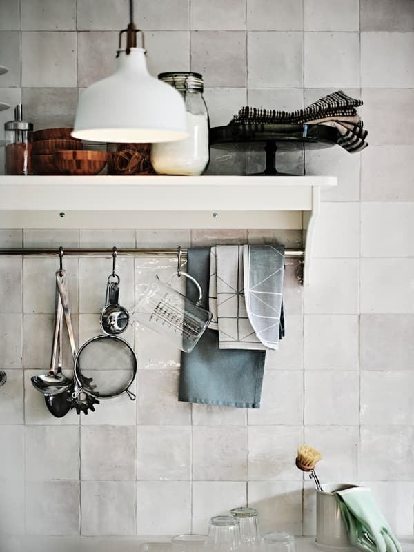 Various kitchen utensils hang on a wall shelf in the kitchen