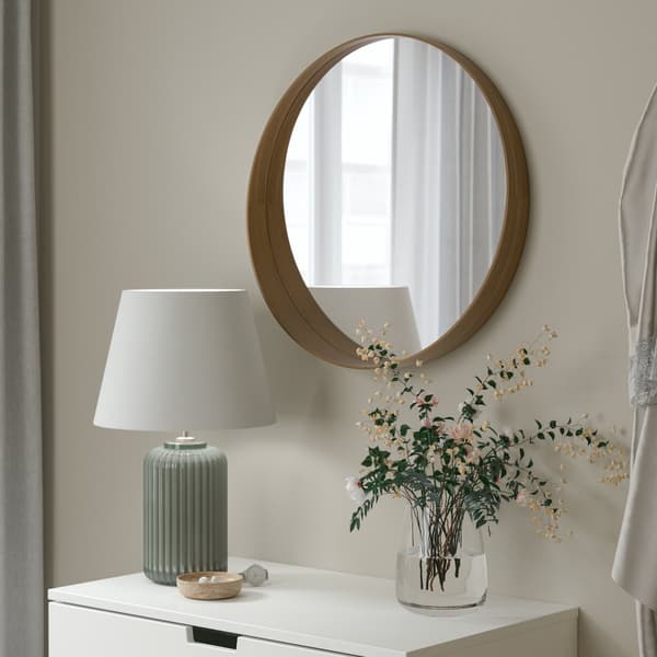 Various sizes of round mirrors with rattan frames are hung on a dark wooden surface to form a focal point.