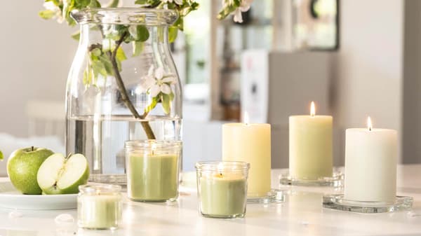 Various white and green scented candles in a kitchen.