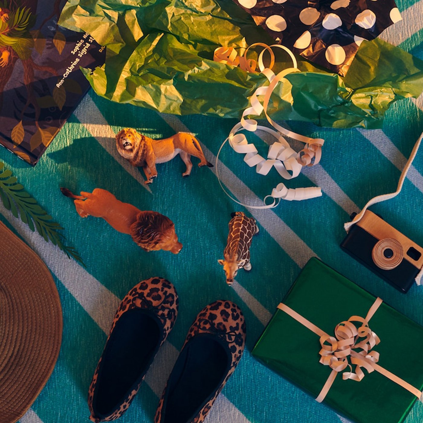 Various wrapped and unboxed gifts and toys along the theme of exploration and adventure lying on a GRACIÖS rug.