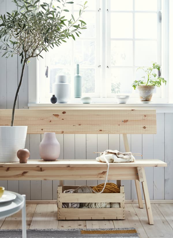 Vase rose et pelotes de laine sur un banc IKEA INDUSTRIELL en pin non traité.