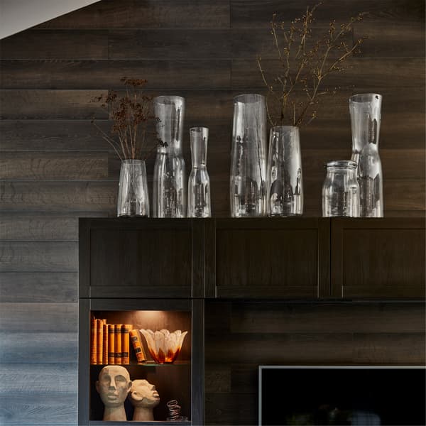 Vases en verre transparent TIDVATTEN sur une combinaison rangement TV dont les tablettes éclairées accueillent livres et objets décoratifs.