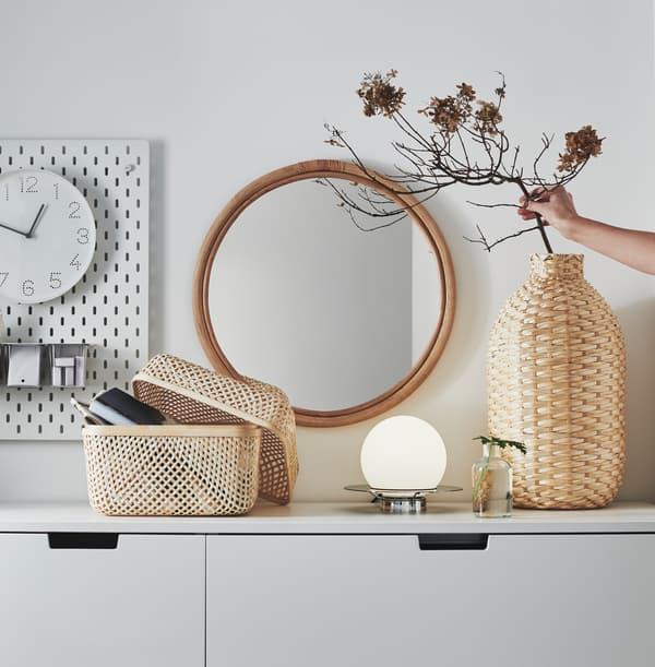 Vaso decorativo KAFFEBÖNA e scatola con coperchio SMARRA, entrambi in bambù, su un mobile bianco.