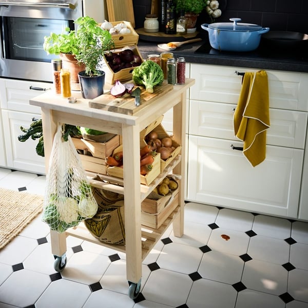 Vastupidav BEKVÄM ratastega köögisaar, millel on värsked ürdid ja köögiviljad traditsioonilises stiilis köögis.