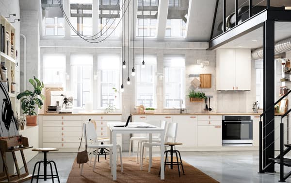 VEDDINGE smooth white cabinet doors arranged across an entire kitchen wall in an open space loft apartment.