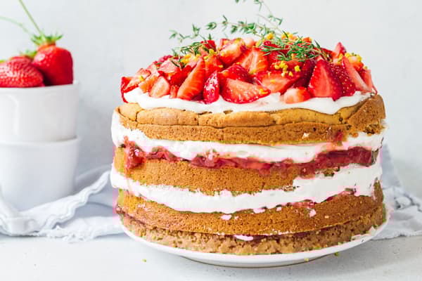 Vegan Strawberry Naked Cake with layers of biscuit, cream and strawberries on a white plate.