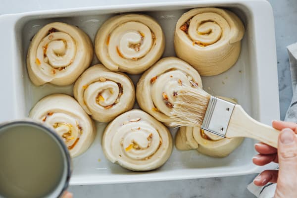 Vegane Hefeschnecken werden mit Haferdrink bepinselt.