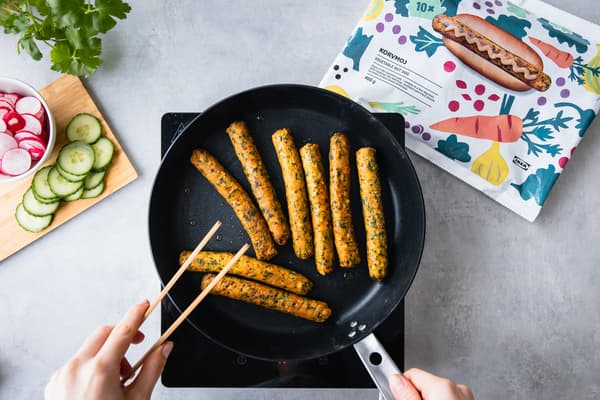 Vegane Würstchen werden in einer Pfanne angebraten.