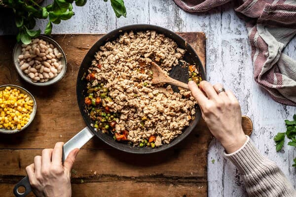 Veganes Hack wird mit gedünstetem Gemüse in einer Pfanne angebraten.