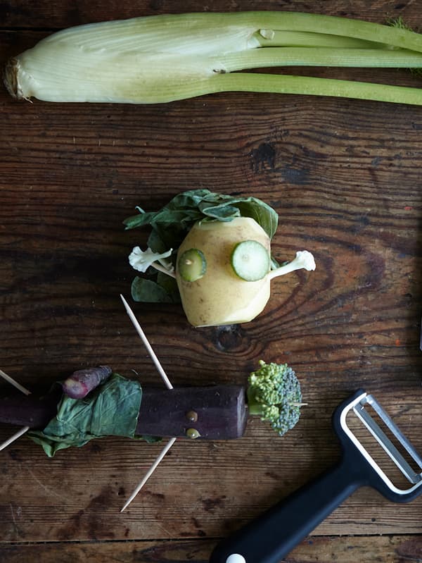 Vegetables cut into the shape of little men and stuck together using toothpicks on a wooden table top with a SMÅBIT peeler.