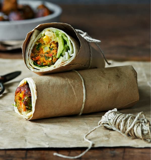 Veggie ball wrap with avocado served in parchment paper held together with a string.