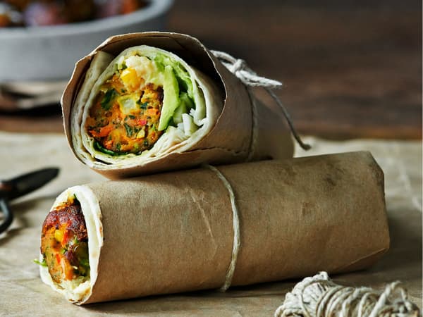 Veggie ball wrap with avocado served in parchment paper held together with a string.